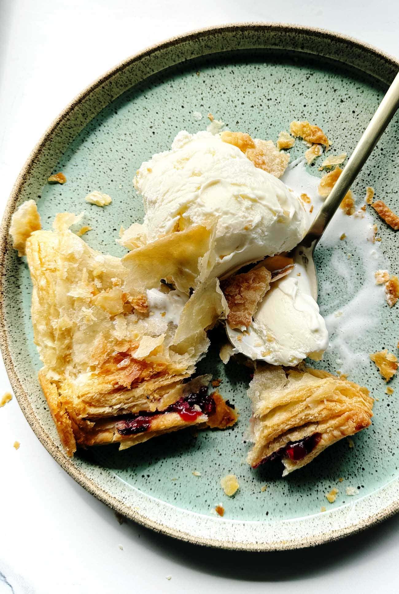 cherry turnover with vanilla ice cream on green plate.